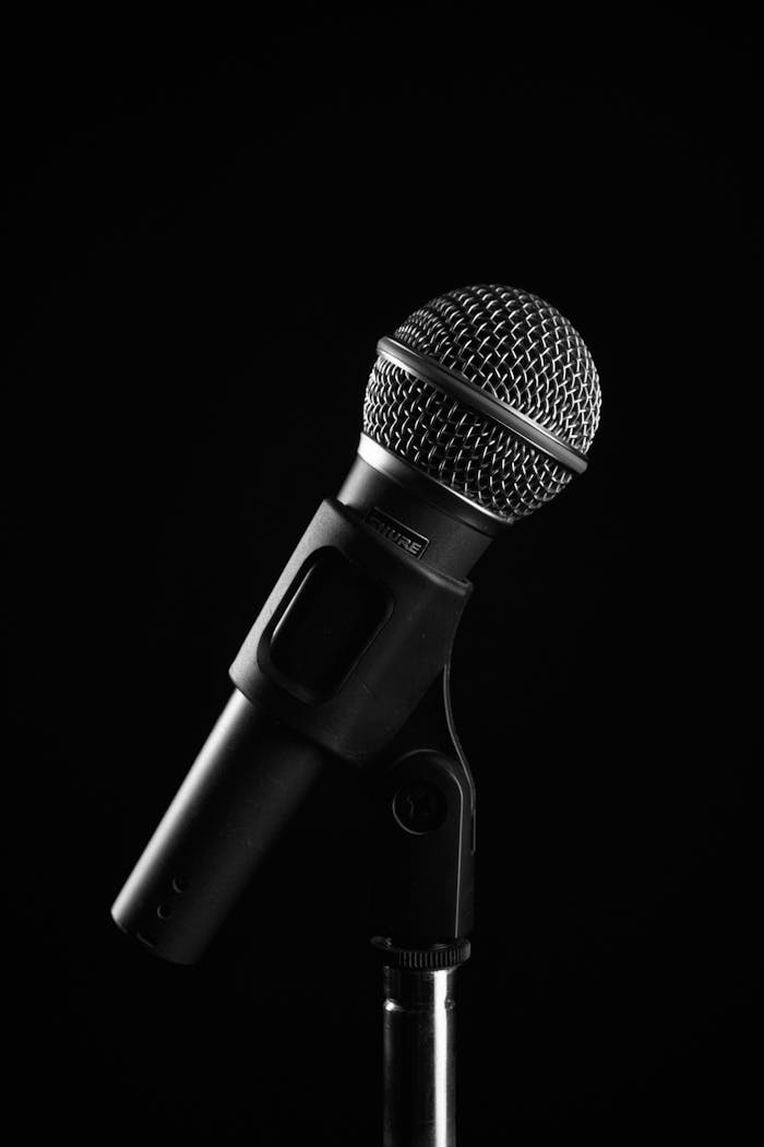 Studio shot of a microphone on a stand with a black background, ideal for audio and music concepts.